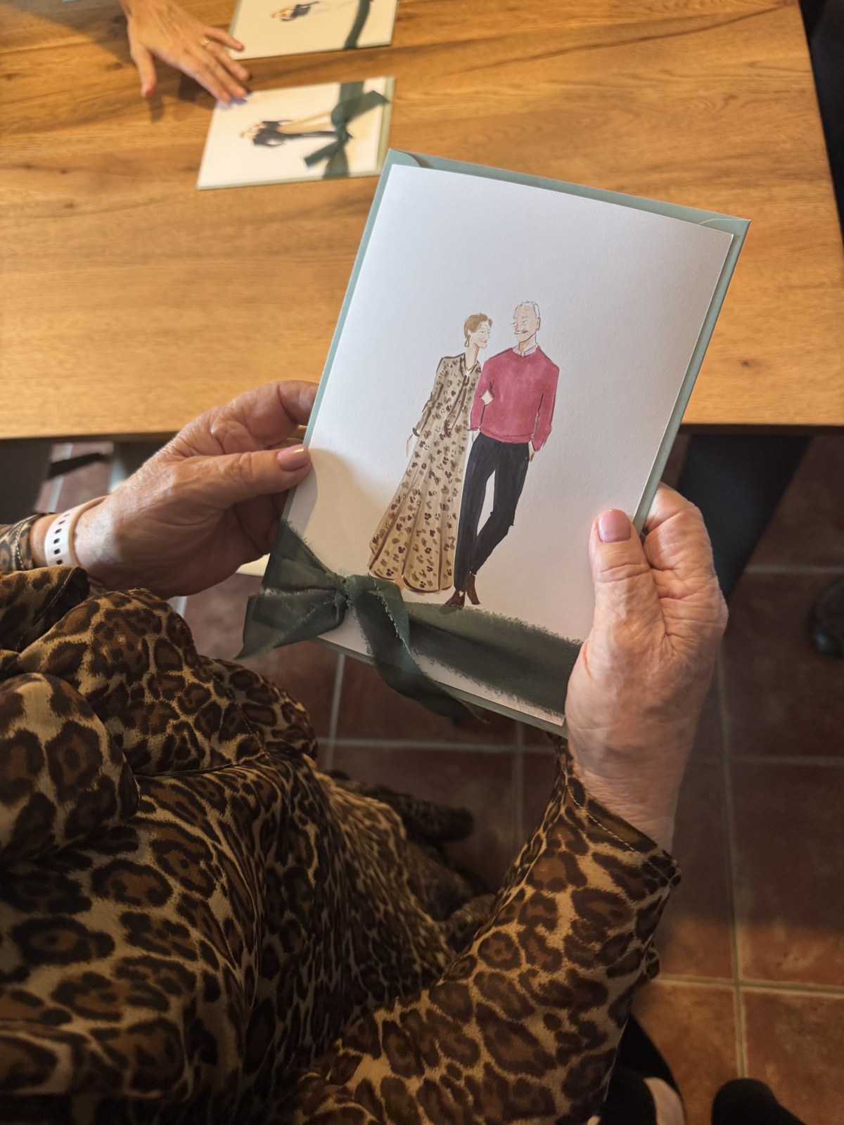 Una invitada sostiene entre las manos la ilustración de una pareja con su sobre verde