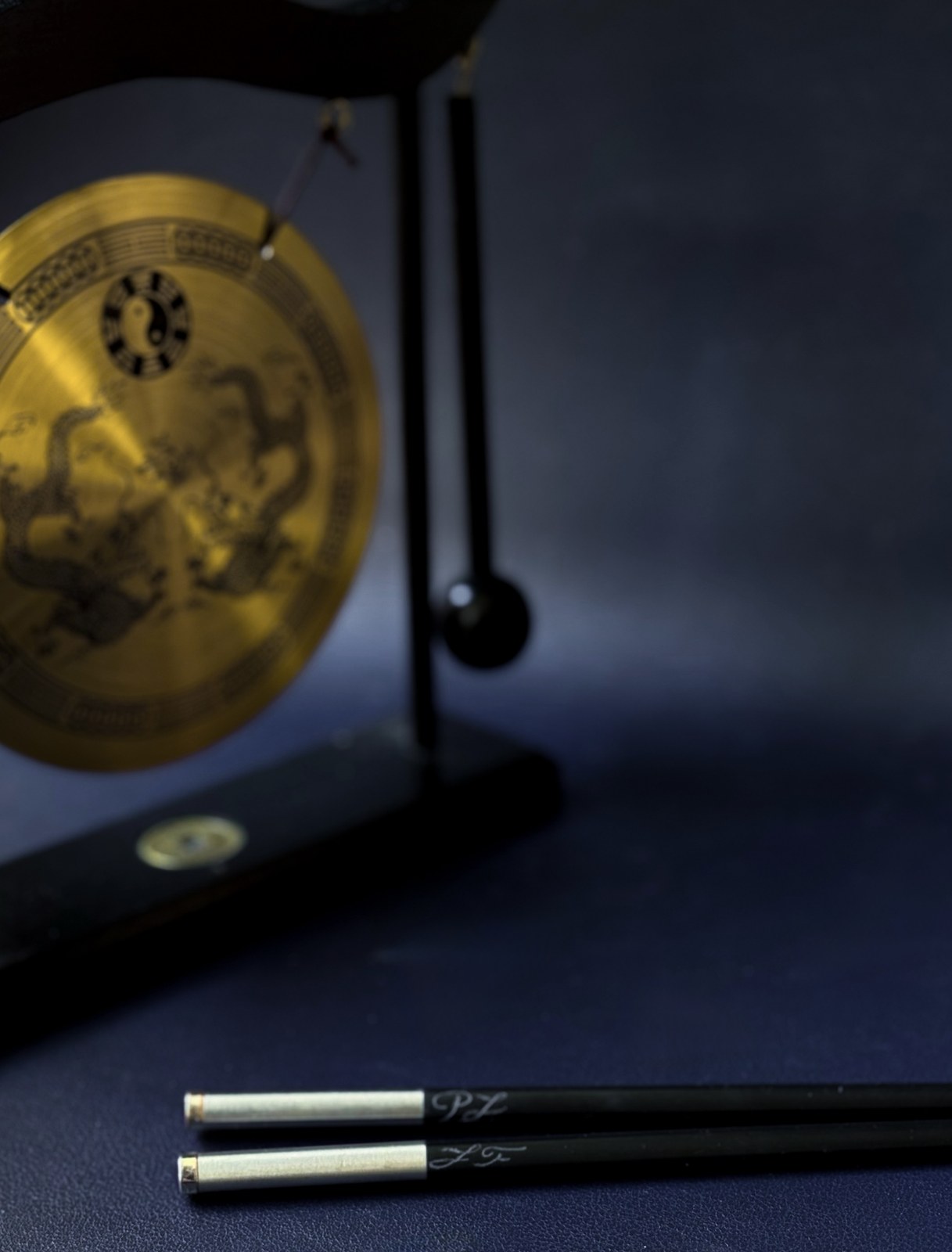 Palillos japoneses con iniciales grabadas junto al gong dorado de la sesión
